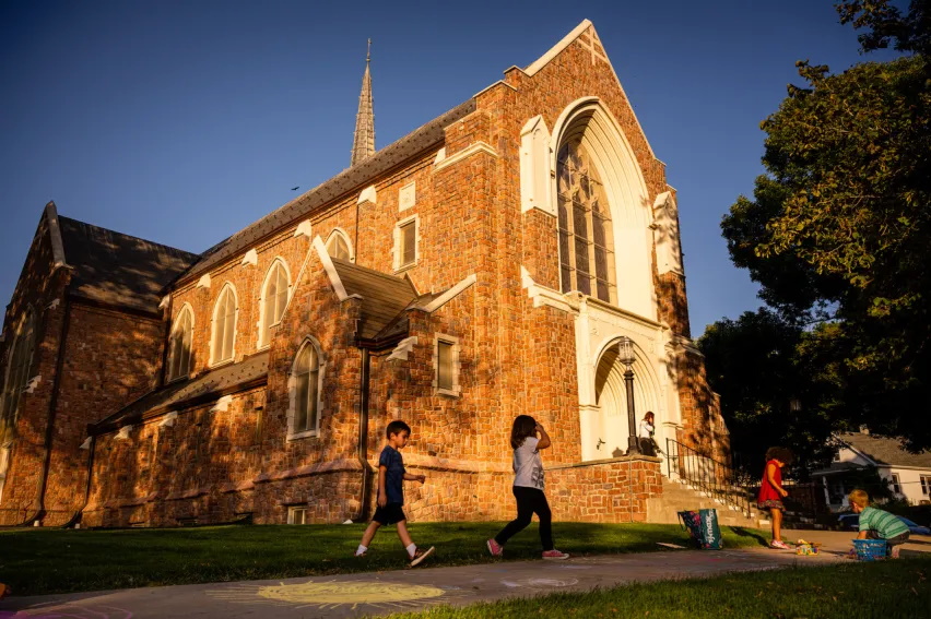 Exterior of St. Paul's Lutheran Church, Council Bluffs, with children playing outside at golden hour.
